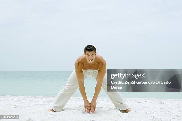 man standing on beach, stretching and smiling at camera, full length - man standing full body stock pictures, royalty-free photos & images