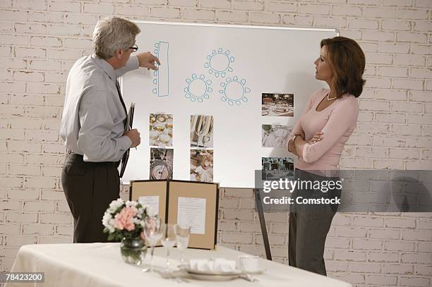 woman looking at seating arrangements with wedding planner - event planner stock pictures, royalty-free photos & images