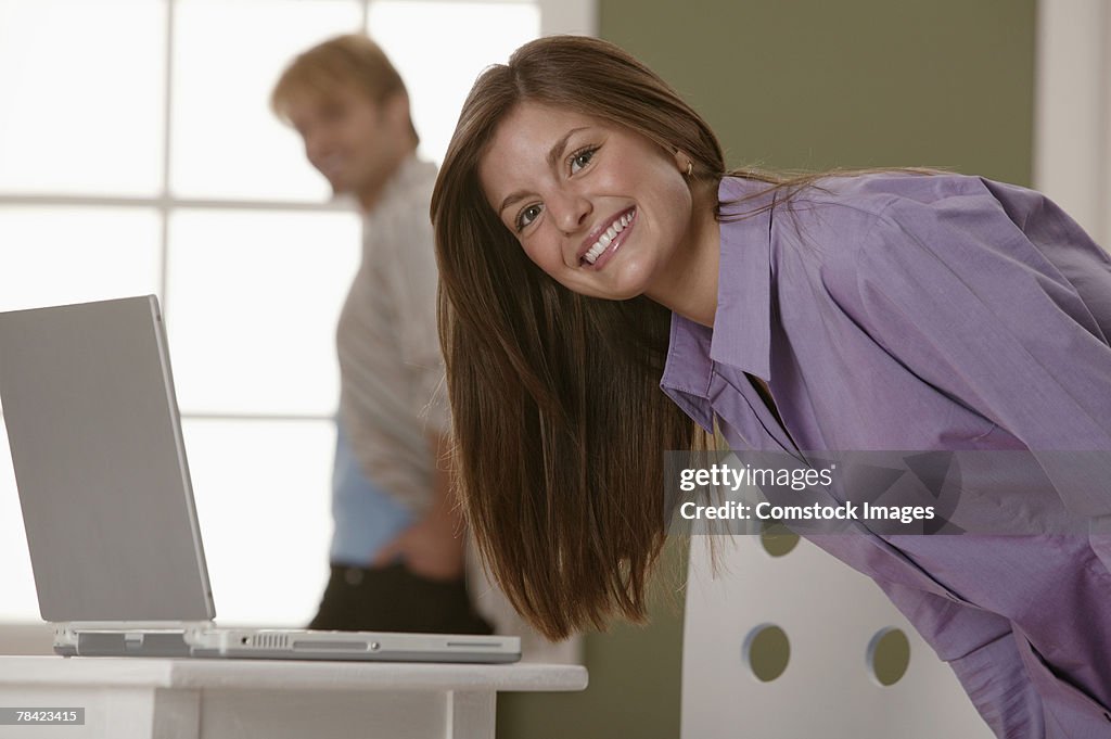 Woman bending over and smiling in front of laptop