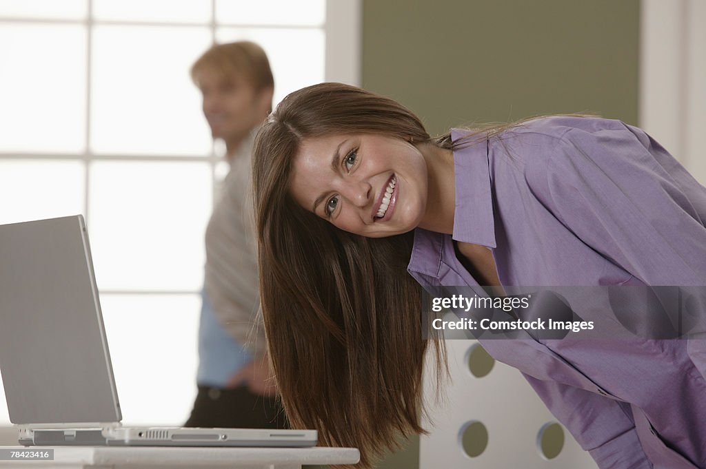 Woman bending over and smiling in front of laptop