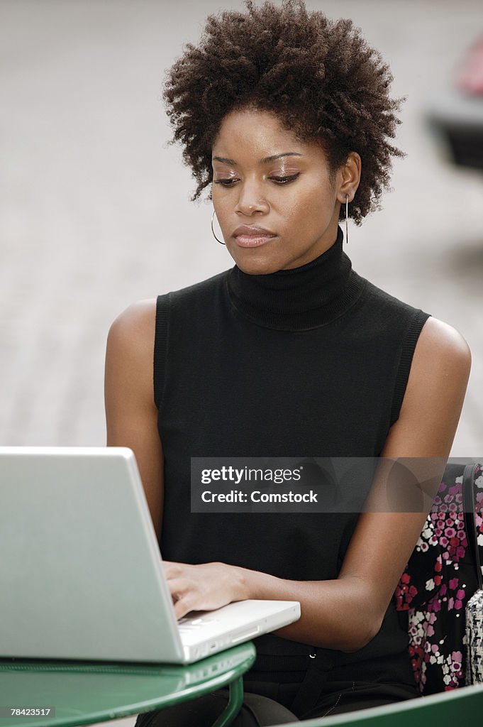 Woman working on laptop at outdoor cafe