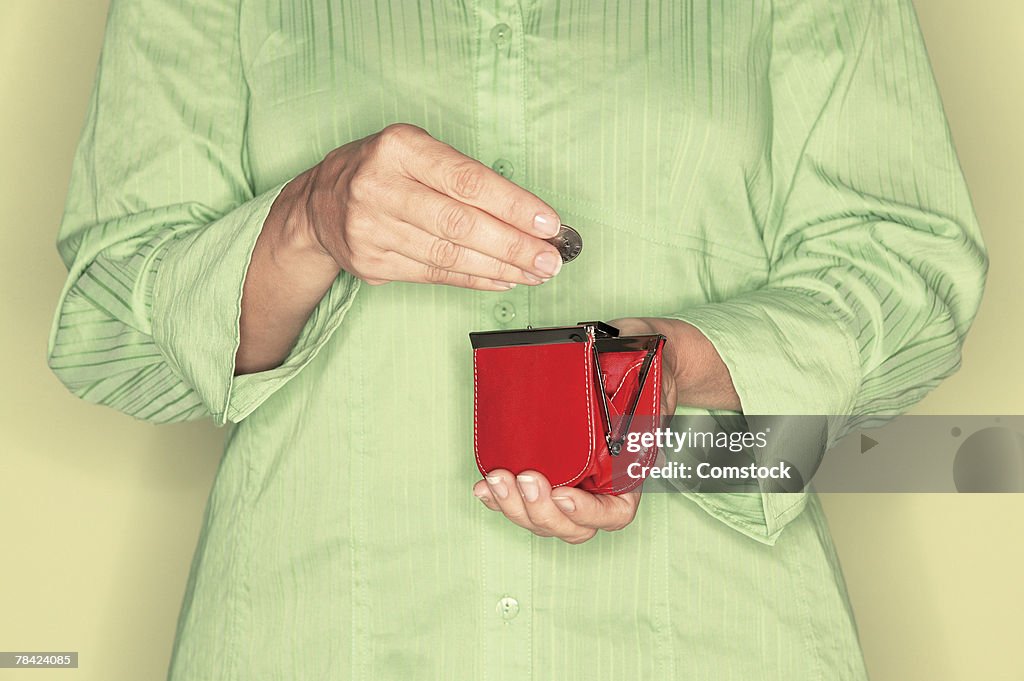 Cropped view of woman putting coin into coin purse