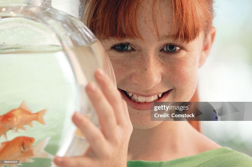 Smiling girl holding goldfish bowl