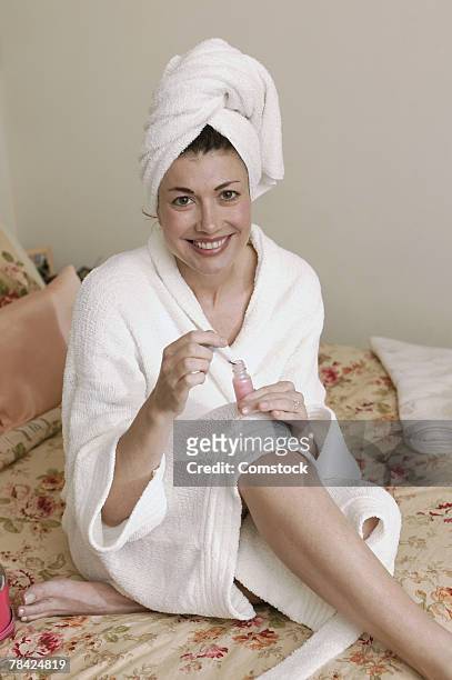 woman sitting in bed putting on nail polish - home manicure stock pictures, royalty-free photos & images