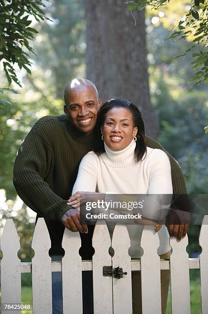 couple standing behind white picket fence - white picket gate stock pictures, royalty-free photos & images