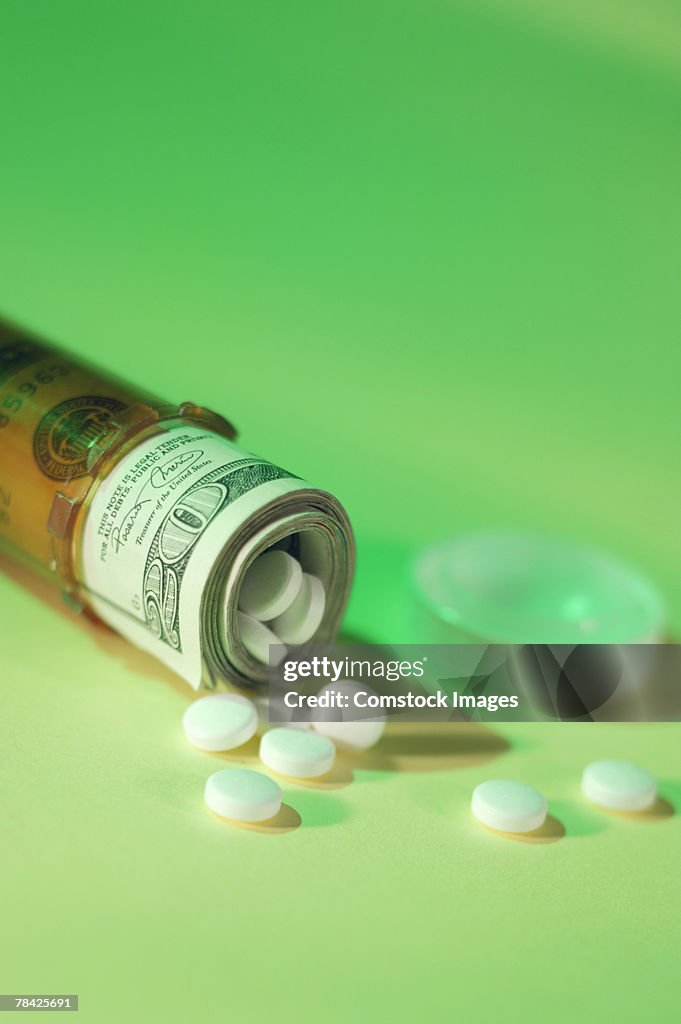 Roll of money and pills in prescription bottle
