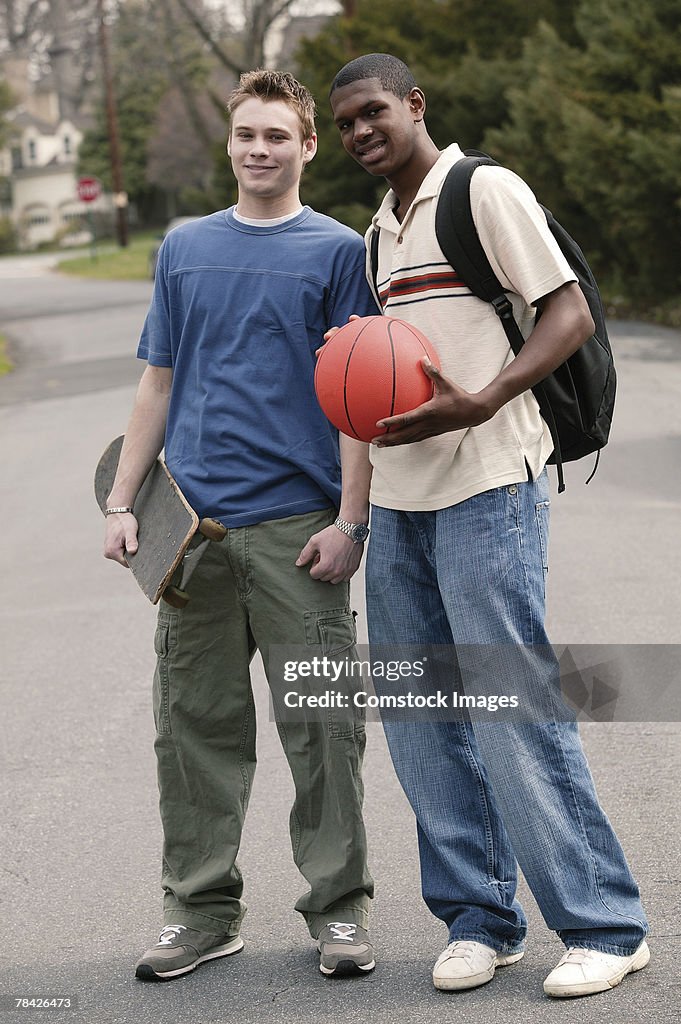 Teenage boys with basketball and skateboard