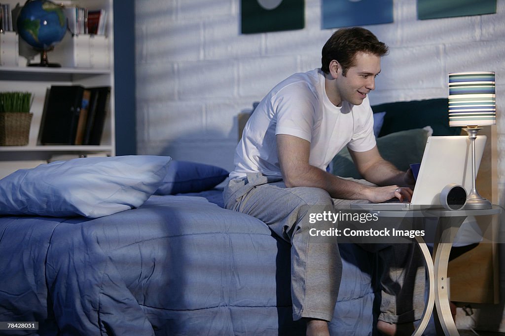 Man using laptop in bedroom