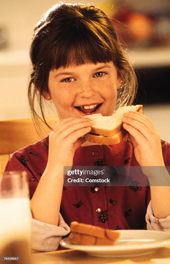 Girl sitting at table eating a sandwich