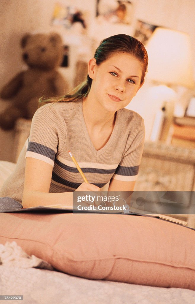 Teenage girl in bedroom doing homework