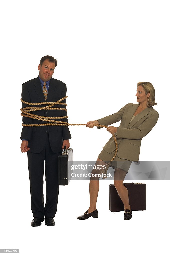 Businessman with briefcase tied up by businesswoman