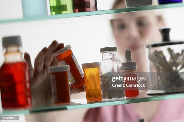woman taking pills from medicine cabinet - armoire de toilette photos et images de collection