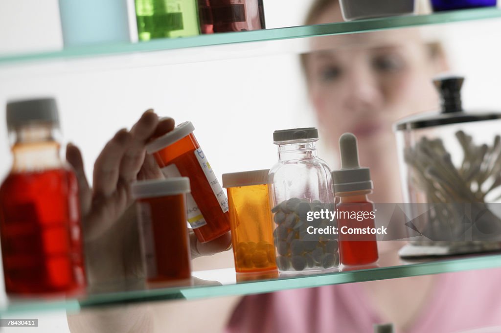 Woman taking pills from medicine cabinet
