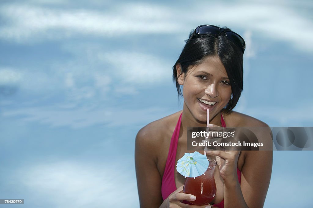 Woman drinking cocktail poolside