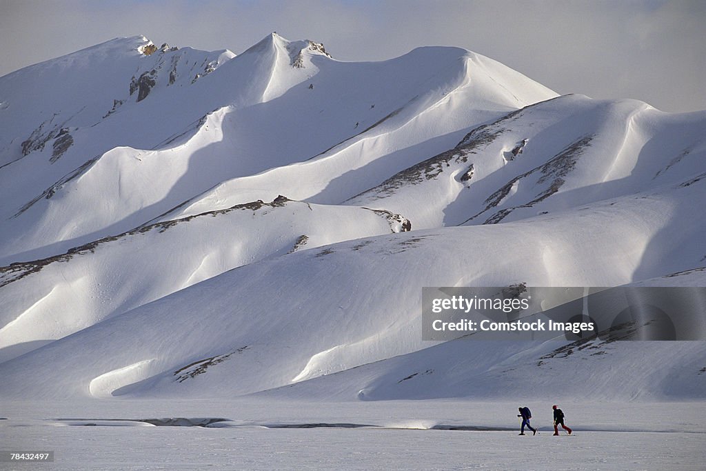 People cross-country skiing by snowy mountain