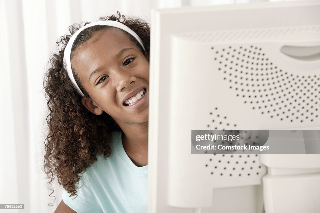 Girl peering from behind computer screen