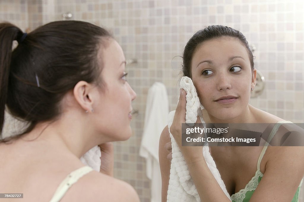 Woman drying face with towel in mirror