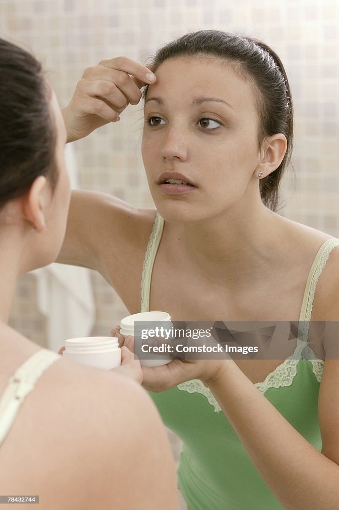 Woman applying moisturizer to face