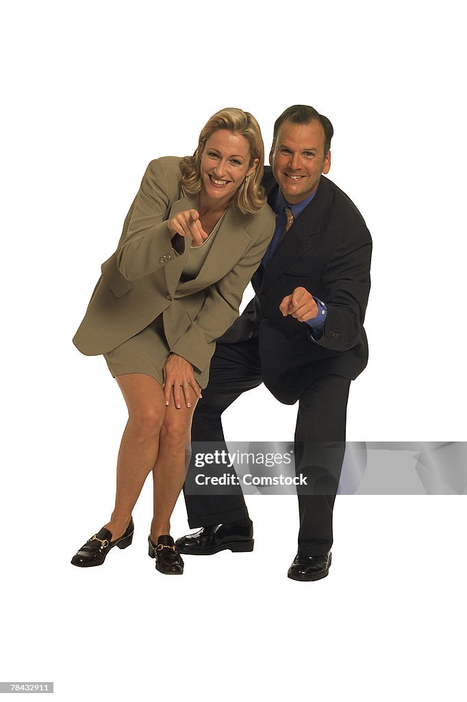 Businessman and woman pointing at you