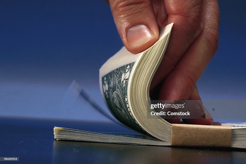 Man fanning bundle of dollar bills