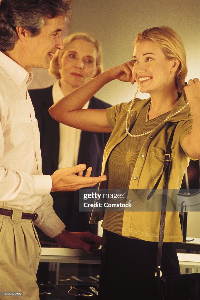 Woman trying on necklace with man and woman looking on