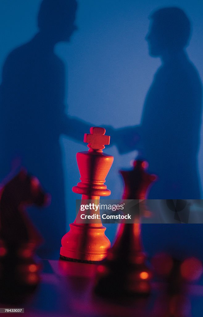 Silhouette of businessmen with chess pieces in foreground