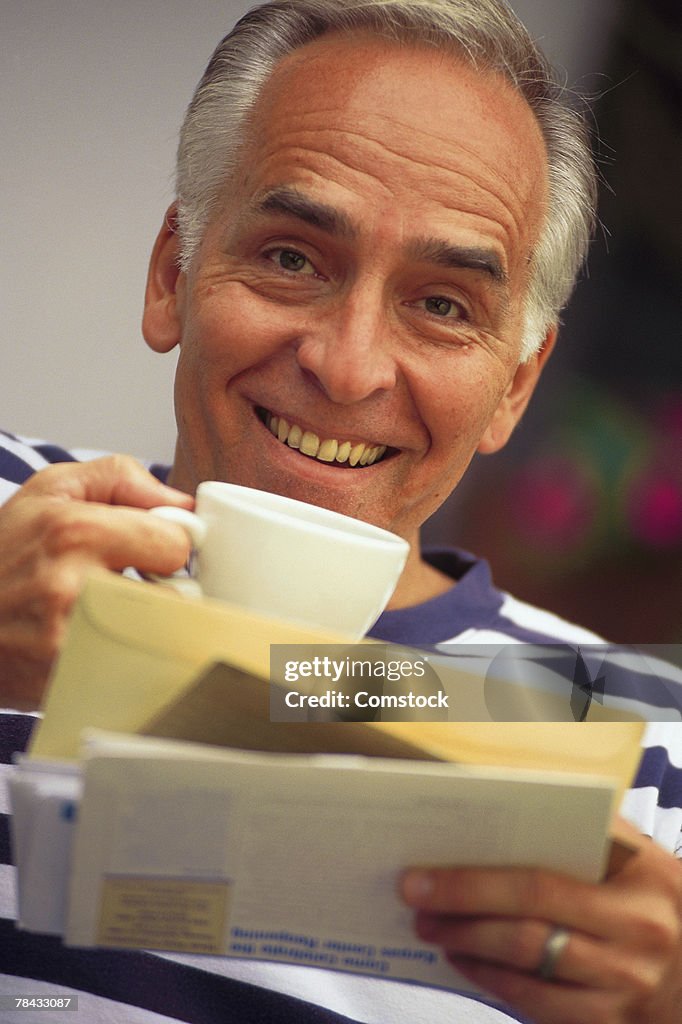 Man looking at bills while drinking coffee