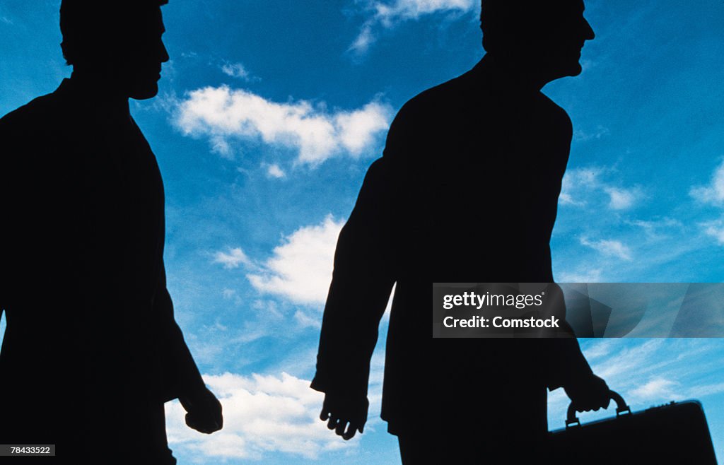 Silhouetted businessmen against sky