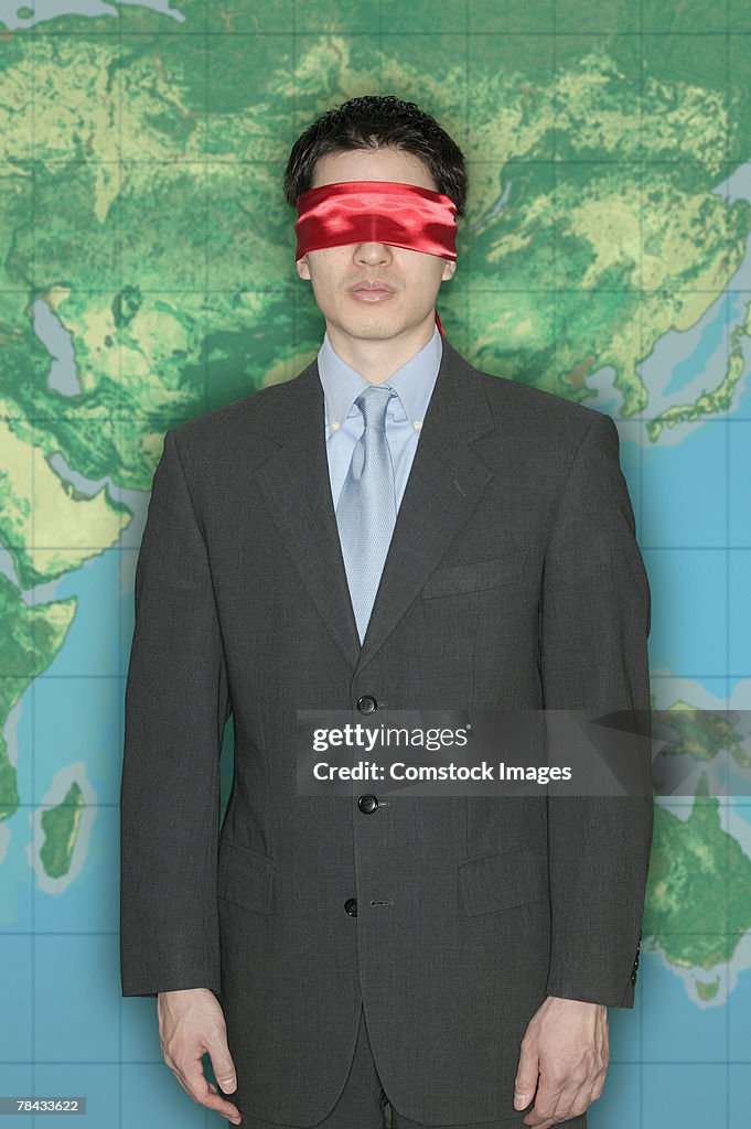 Blindfolded businessman in front of world map