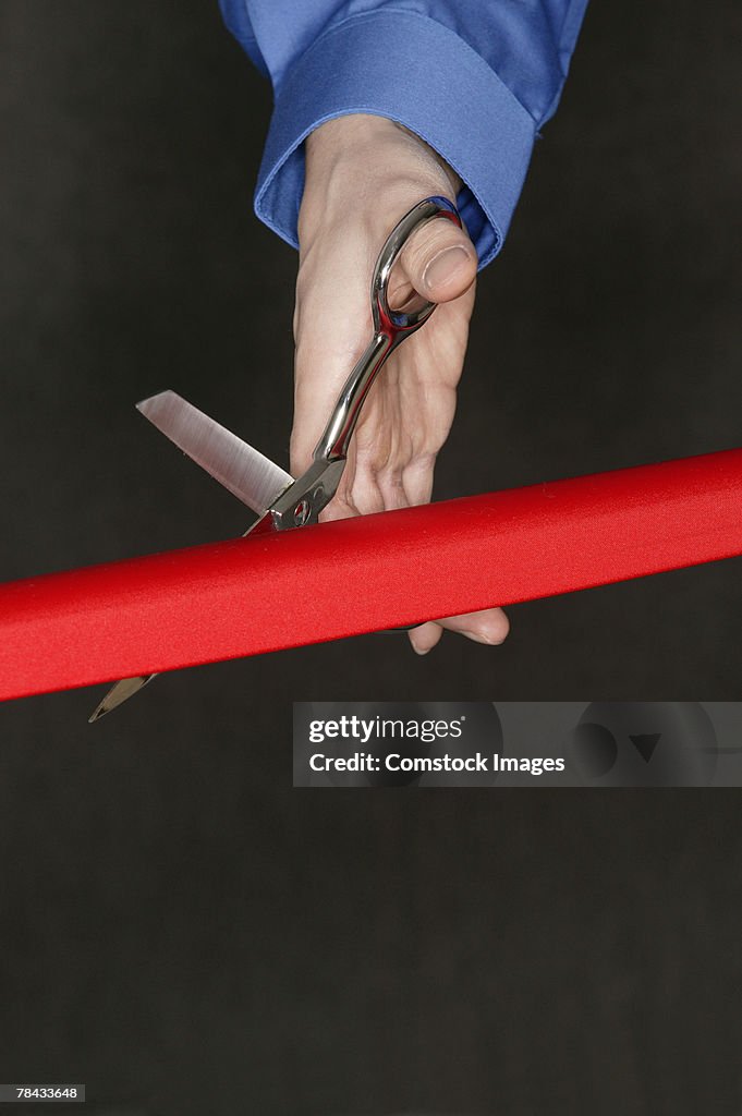 Hand cutting red tape