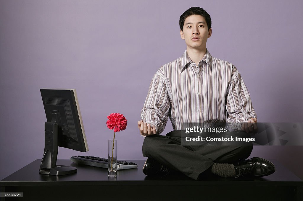 Businessman meditating on top of desk