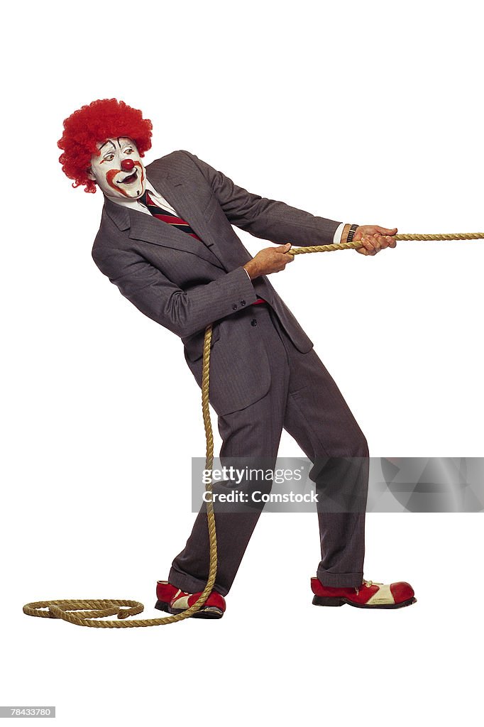 Clown in business suit tugging on rope