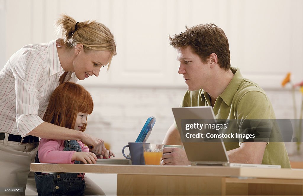 Parents teaching daughter to use toy computer