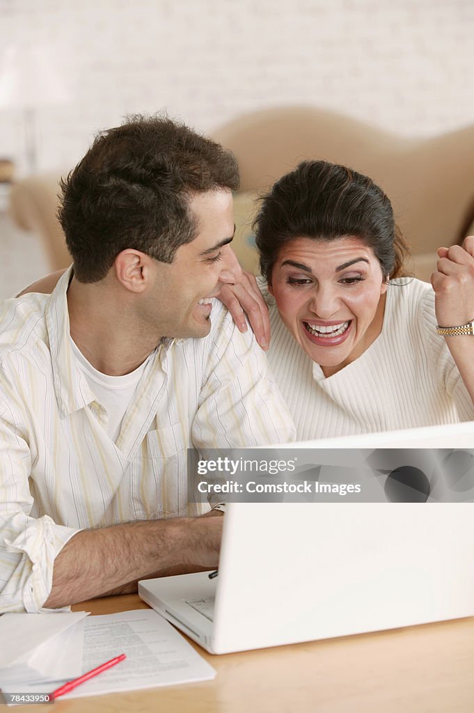 Excited woman using laptop at home