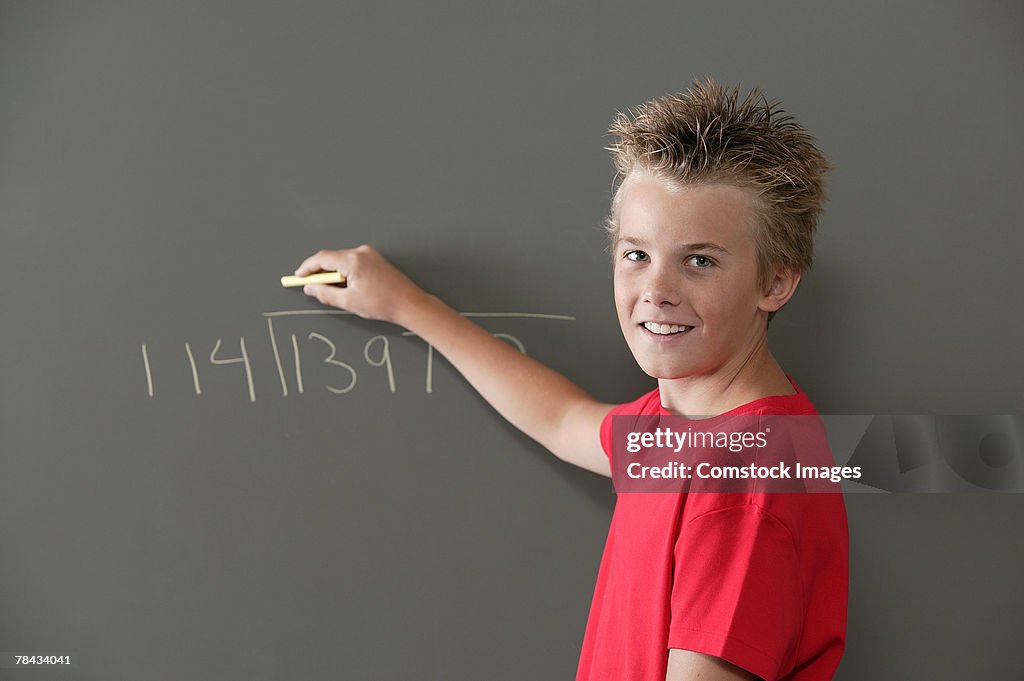 Boy writing on blackboard