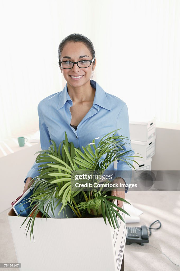 Businesswoman carrying box of stuff out of office