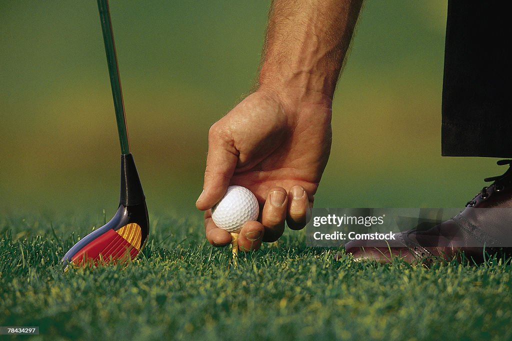 Golfer placing ball on tee