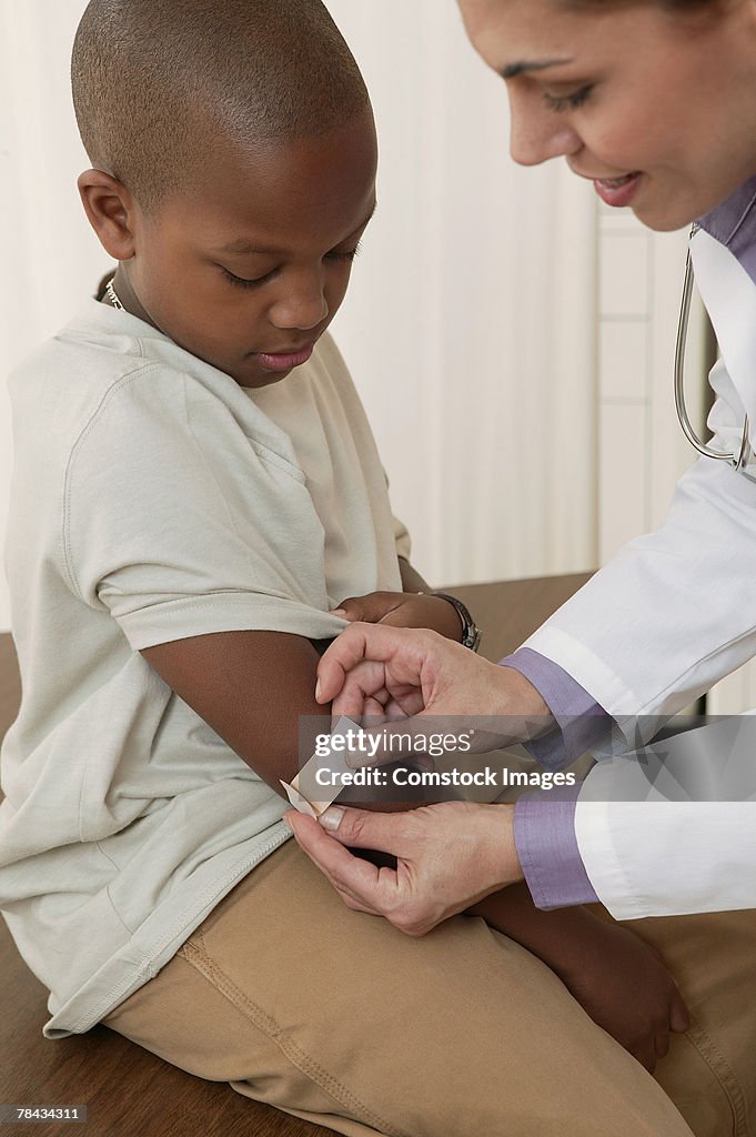 Doctor putting adhesive bandage on boy