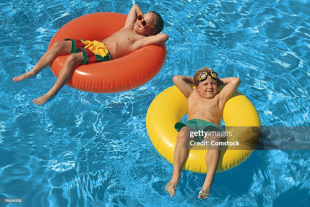 Young boys floating in inner tubes in swimming pool