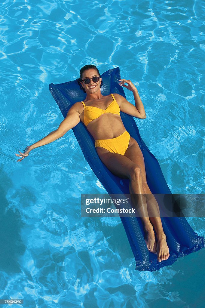 Woman floating on raft in swimming pool