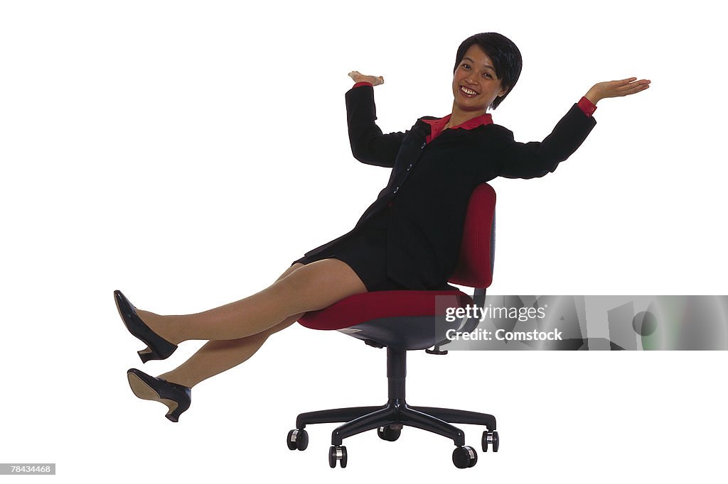 Businesswoman in office chair rolling across floor