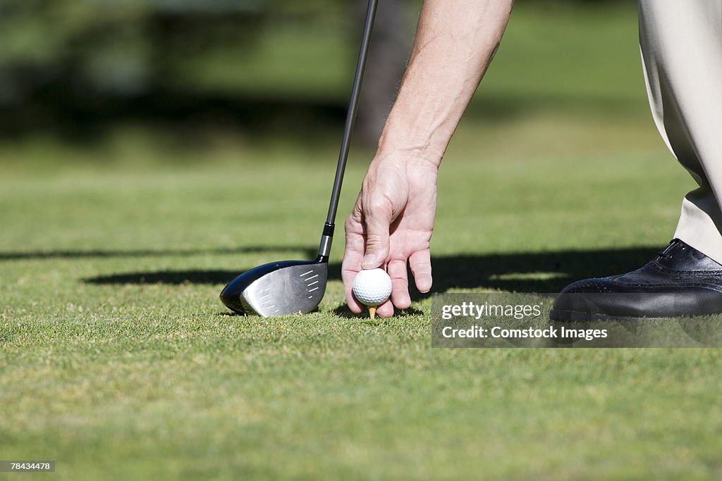 Hand putting golf ball on tee