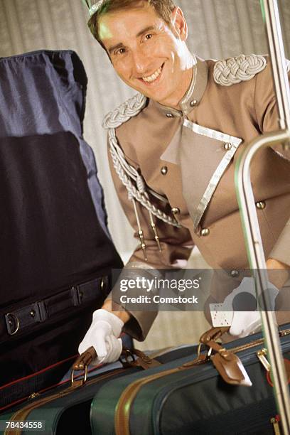 bellhop with luggage in hotel - bell boy stock pictures, royalty-free photos & images