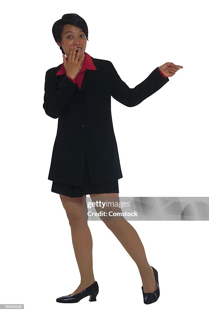 Businesswoman with hand covering mouth and pointing