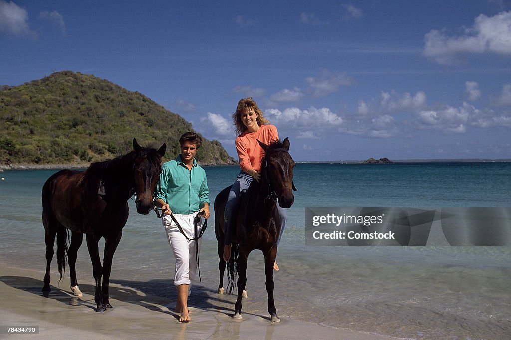 Couple riding horses on the beach