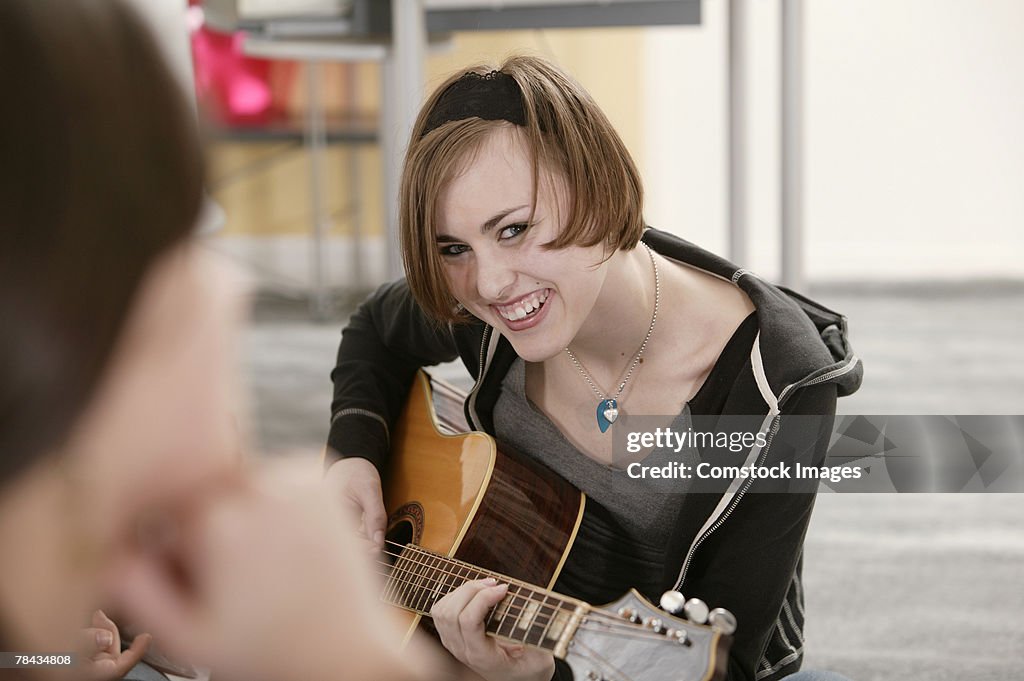 Teenage girl playing guitar with friends