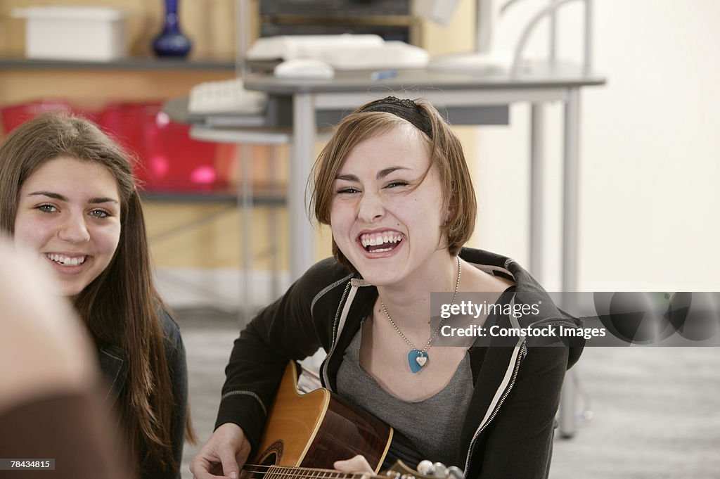 Teenage girl playing guitar and laughing