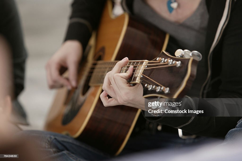 Close-up of teenage girl playing guitar