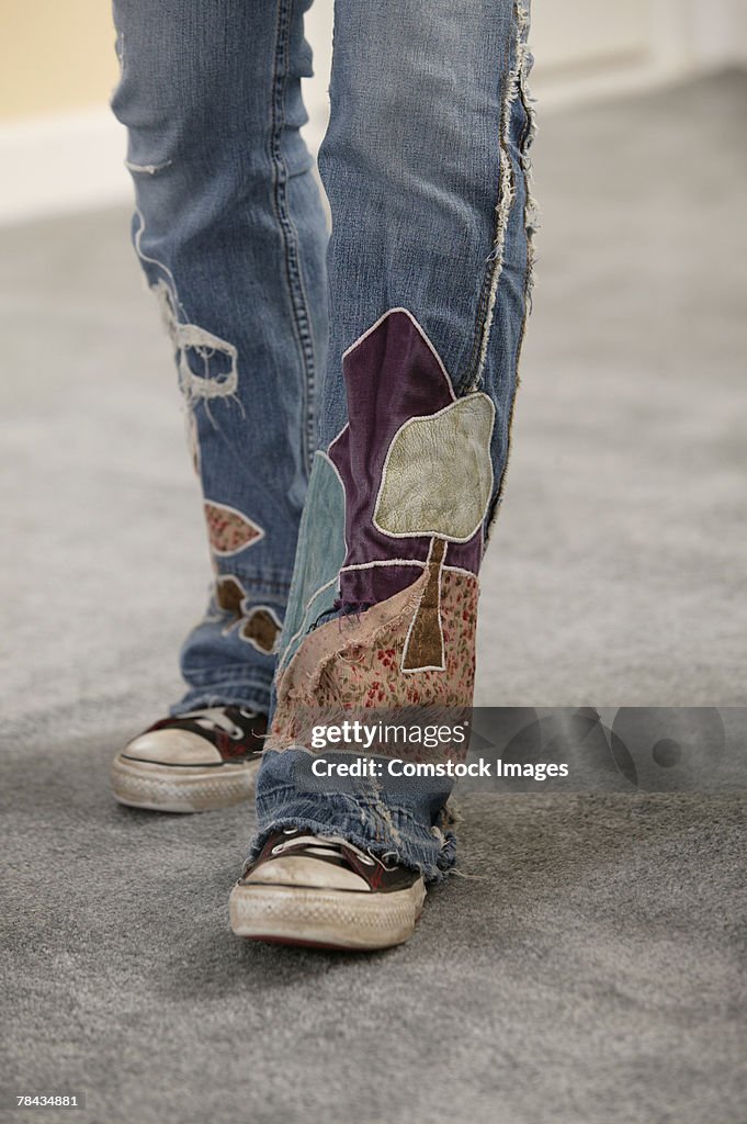 Legs of person wearing jeans with patches