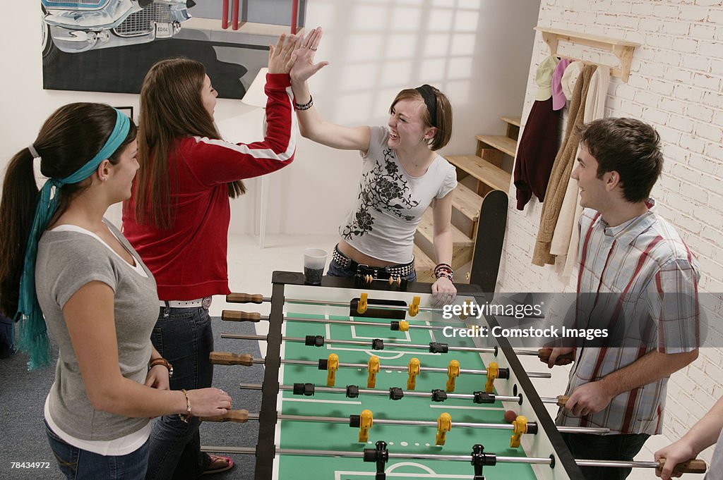 Group of teenage friends playing table soccer